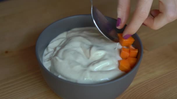 Closeup shot of a process of making a smoothie bowl with papaya, dragon fruit, granola, dried cherry, and pumpkin seeds — Stock Video