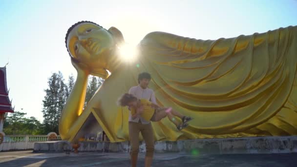 Plan au ralenti d'un jeune homme et de son petit fils s'amusant devant une statue du Bouddha couché sur l'île de Phuket. Voyager en Thaïlande concept — Video