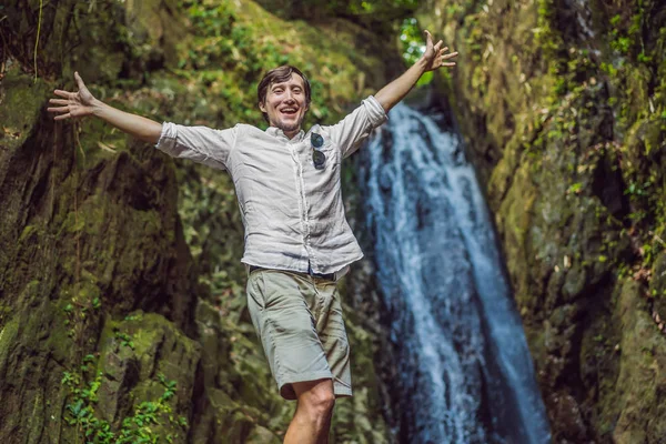 素晴らしい熱帯の滝を楽しむ幸せな男は、背景の山の野生の自然に旅行ライフスタイルと成功コンセプトの休暇を上げました — ストック写真