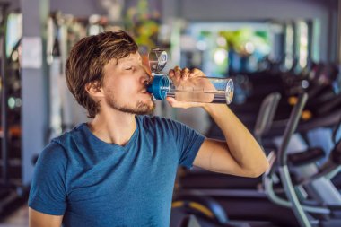 Spor salonunda su içen adam.