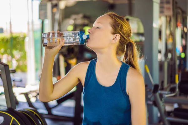Young athletic woman drinking water in gym — Stock Photo, Image