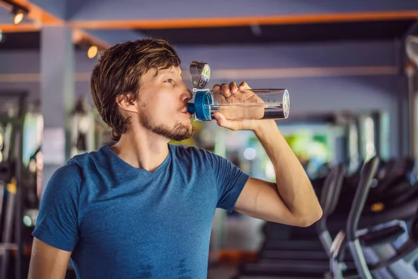 Спортсмен п'є воду в спортзалі — стокове фото