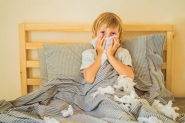 Sick boy coughs and wipes his nose with wipes. Sick child with fever and illness in bed — Stock Photo, Image