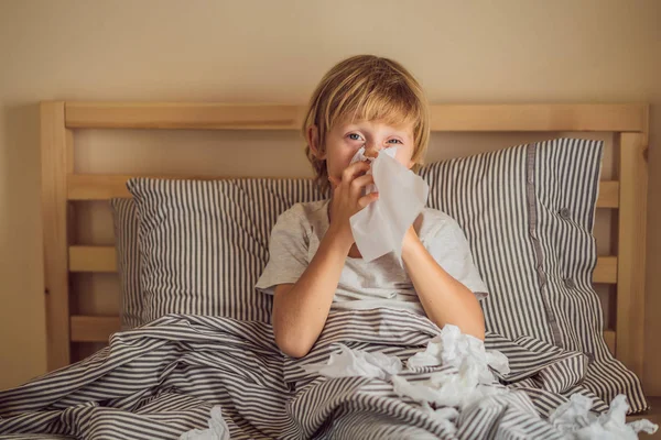 Sick boy coughs and wipes his nose with wipes. Sick child with fever and illness in bed — Stock Photo, Image