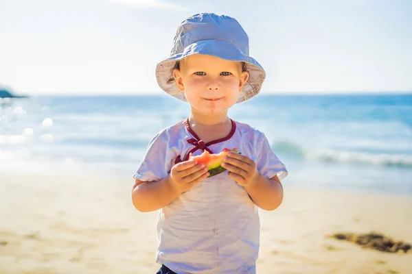 Menino comendo melancia na praia contra o mar — Fotografia de Stock