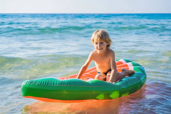 Мальчик плавает в море на надувном матрасе — стоковое фото