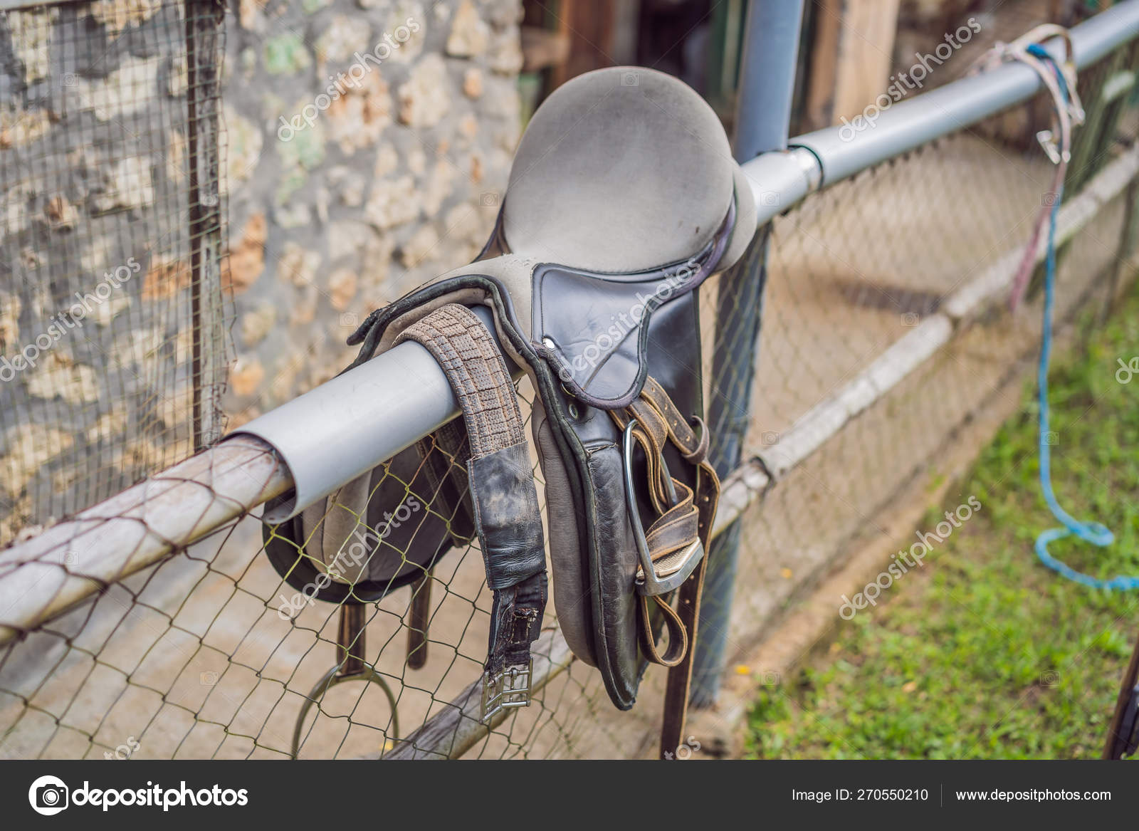 A saddle laying on the rustic fence in warm day Stock Photo by