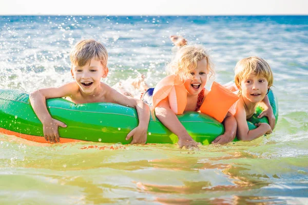 I bambini nuotano in mare su un materasso gonfiabile e divertiti — Foto Stock