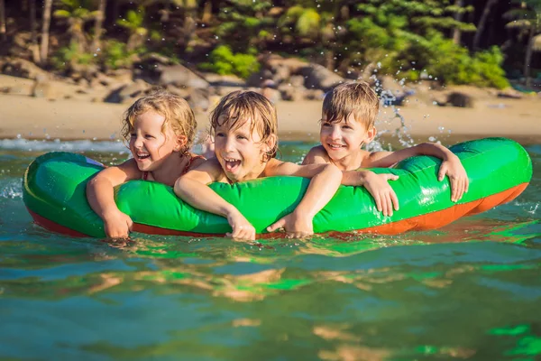 Τα παιδιά κολυμπούν στη θάλασσα σε ένα φουσκωτό στρώμα και διασκεδάζουν — Φωτογραφία Αρχείου