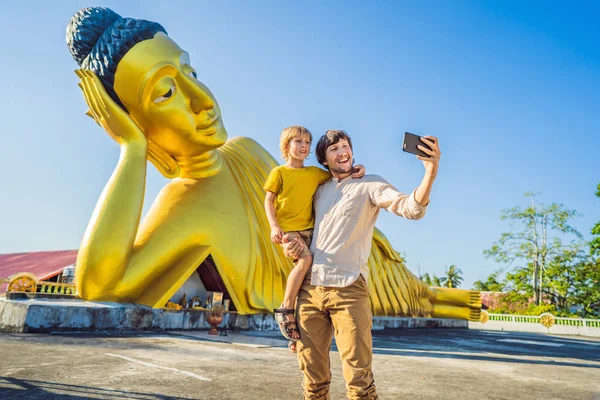 Gelukkige toeristen vader en zoon op achtergrond oflying Boeddha standbeeld — Stockfoto