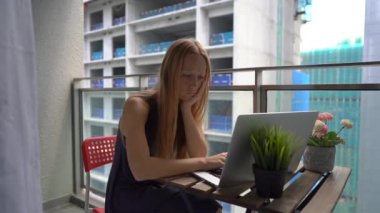 Slowmotion bir dizüstü bilgisayar ile bir balkonda oturan ve yakın bir inşaat sitesi tarafından üretilen bir yüksek gürültü muzdarip genç bir kadın vurdu. Büyük şehirlerde gürültü kirliliği kavramı