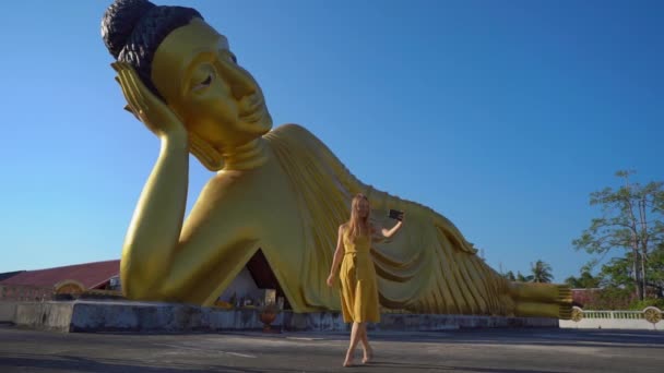 プーケット島に横たわる仏像を持つワット・ススーンソーン寺院を訪れる若い女性旅行者のスローモーションショット。タイへの旅のコンセプト — ストック動画