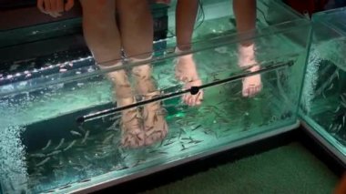 2x kez slowmotion genç bir kadın ve küçük oğlu bir balık spa ziyaret çekim. Kozmetik prosedür balık soyma