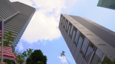 Bir akıllı telefon tutan ve arka planda gökdelenler ile Malezya bayrağı dalgalar genç bir adamın Slowmotion çekim. Malezya'ya seyahat konsepti