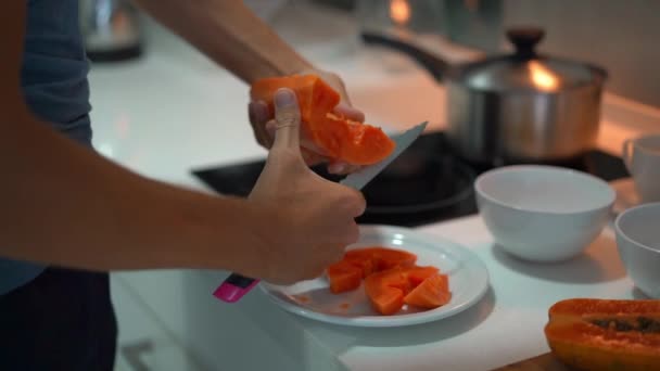 Plan lent d'un jeune homme dans une cuisine préparant le petit déjeuner avec des fruits tropicaux frais pour sa famille — Video