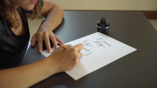 Plan rapproché d'une jeune femme en calligraphie écrivant sur un papier en utilisant la technique du lettrage. Elle écrit Rêve grand fixer des objectifs Agir — Video