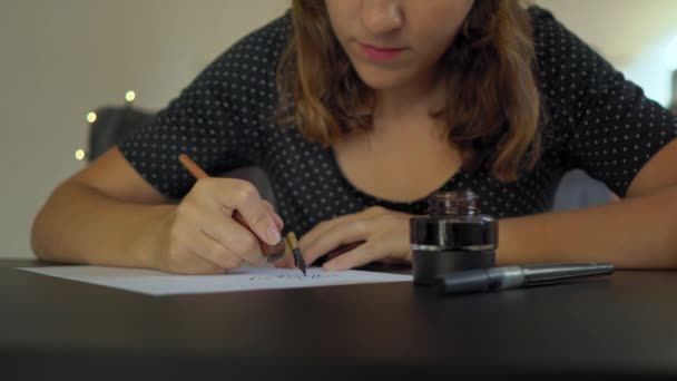 Primer plano de una joven caligrafía escribiendo en un papel usando técnica de letras — Vídeo de stock