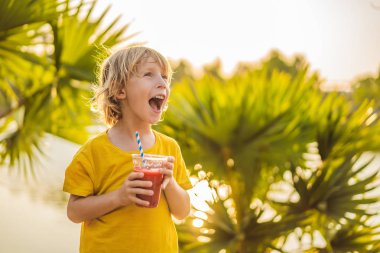 Çocuk palmiye ağaçlarının arka planında sağlıklı smoothies içmek. Karpuz smoothies. Çocuklar için sağlıklı beslenme ve vitaminler