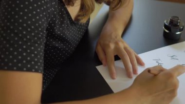 Yazı tekniği ni kullanarak bir kağıda yazan genç bir kadının kaligrafisini yakından kapatın. O rüya büyük Set hedefleri yazılıhareket edin