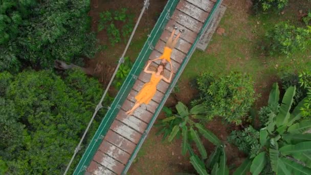 Vue aérienne d'une jeune femme et de son petit fils allongés sur un pont suspendu au-dessus des jungles. Voyage en Asie du Sud-Est concept — Video