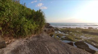 Bali adasında bir Tanah Lot tapınağında kayalık bir sahil üzerinde yürüyen bir ailenin Slowmotion steadicam çekim