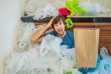 Bir yığın plastik poşetin arasında kağıt torba tutan adam. Sıfır atık kavramı. Dünya Çevre Günü kavramı