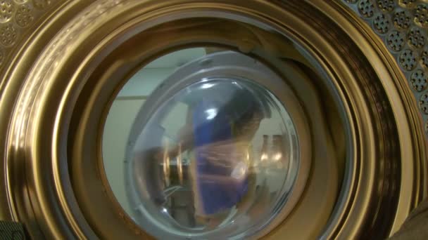 Uitzicht vanaf de wasmachine als een kleine jongen zet vuile kleren in het — Stockvideo