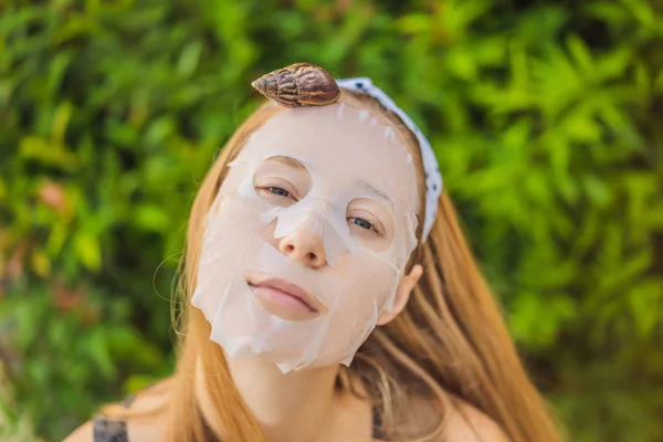 Une jeune femme fait un masque facial avec du mucus d'escargot. Escargot rampant sur un masque facial — Photo