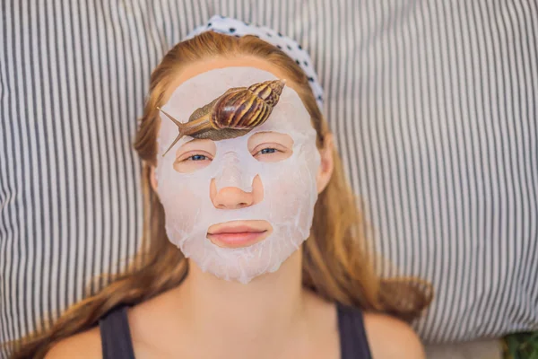 Young woman makes a face mask with snail mucus. Snail crawling on a face mask — Stock Photo, Image