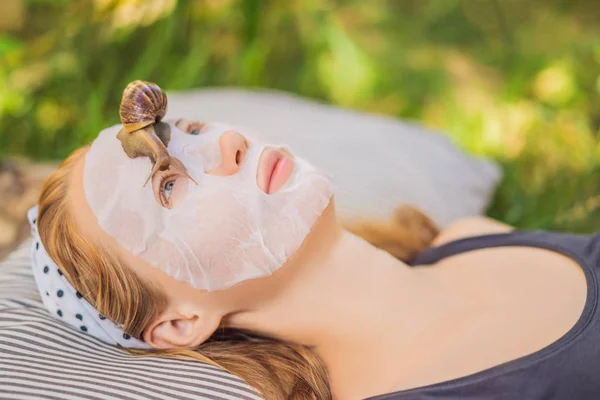 Une jeune femme fait un masque avec du mucus d'escargot. Escargot rampant sur un masque facial — Photo