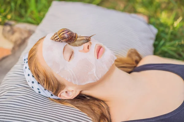 Jovem faz uma máscara facial com muco de caracol. Caracol rastejando em uma máscara facial — Fotografia de Stock