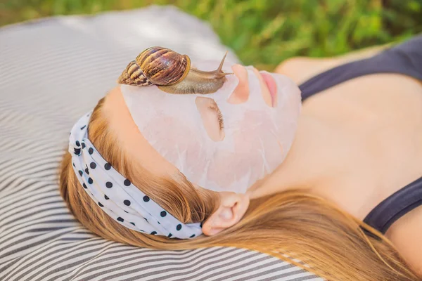 Mujer joven hace una mascarilla con moco de caracol. Caracol arrastrándose sobre una máscara facial — Foto de Stock