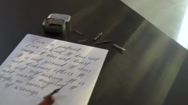Bir hat sanatı araçlarının ve bir şişe mürekyenin üzerinde aşk la ilgili bir İncil'den birkaç satır içeren beyaz bir kağıdın etrafına serpiştirme fotoğrafı