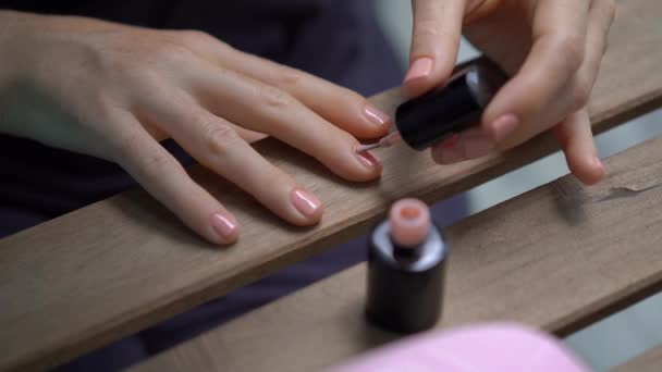 Primer plano de una mujer haciendo su manicura usando gel pulido que se endurece bajo luz ultravioleta — Vídeo de stock