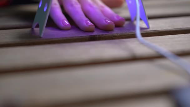 Gros plan d'une femme faisant sa manucure à l'aide d'un vernis gel qui durcit sous la lumière ultraviolette — Video