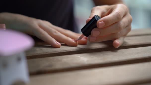 Primer plano de una mujer haciendo su manicura usando gel pulido que se endurece bajo luz ultravioleta — Vídeos de Stock