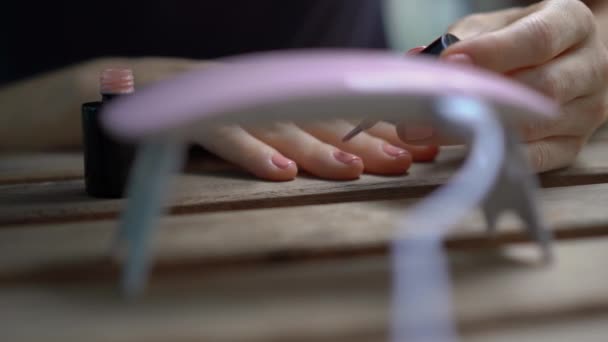 Close-up shot van een vrouw doet haar manicure met behulp van gel Polish die verhardt onder ultraviolet licht — Stockvideo