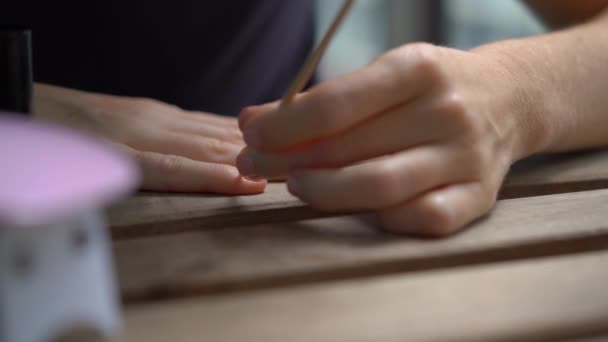 Primer plano de una mujer haciendo su manicura usando gel pulido que se endurece bajo luz ultravioleta — Vídeo de stock