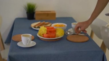 Bir mutfakta aile için taze tropikal meyveler ile kahvaltı hazırlamak bir genç adam
