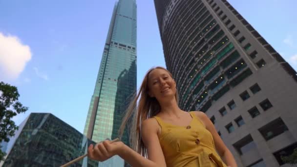 Plan au ralenti d'une jeune femme agitant le drapeau malaisien avec des gratte-ciel en arrière-plan. Voyage en Malaisie concept — Video