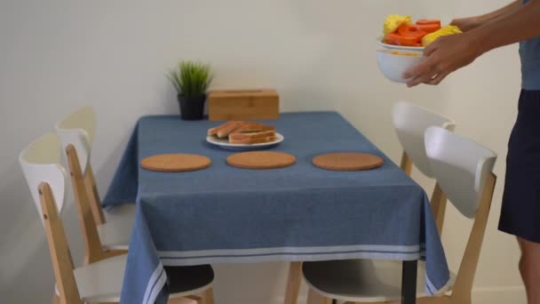 Un jeune homme dans une cuisine préparant le petit déjeuner avec des fruits tropicaux frais pour sa famille — Video