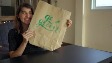 Genç kadın Hattat yazılı bir kağıt çanta yazı tekniği kullanarak yazma yakın. Ona yeşil git yazıyor. Plastik kullanım kavramını azaltın