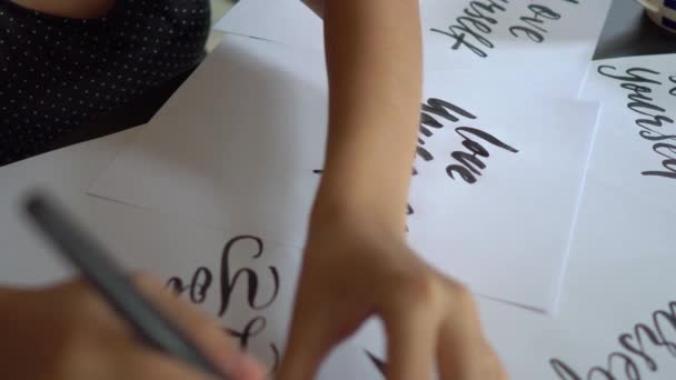 Plan rapproché d'une jeune femme en calligraphie écrivant sur un papier en utilisant la technique du lettrage. Elle écrit Love yourself — Video