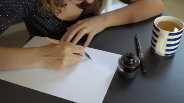 Foto ravvicinata di una giovane donna con un cappello di Natale calligrafia che scrive su un foglio usando la tecnica del lettering. lei scrive Buon Natale — Video Stock