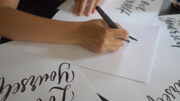 Plan rapproché d'une jeune femme en calligraphie écrivant sur un papier en utilisant la technique du lettrage. Elle écrit Love yourself — Video