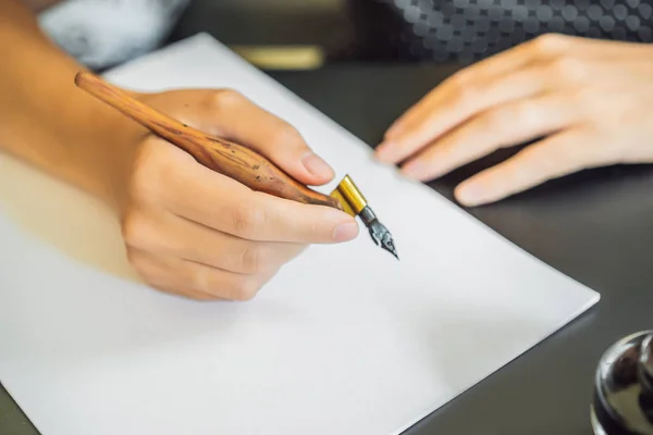 Calígrafa Joven escribe frase en papel blanco. Inscribiendo letras ornamentales decoradas. Caligrafía, diseño gráfico, letras, escritura a mano, concepto de creación —  Fotos de Stock