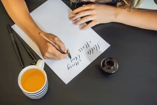 La calligrafa Young Woman scrive frasi su carta bianca. Inscrivendo lettere ornamentali decorate. Calligrafia, grafica, lettering, calligrafia, concetto di creazione — Foto Stock