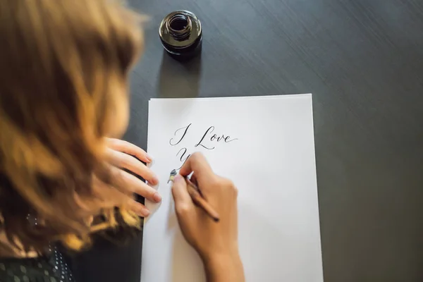 Szeretlek. Kalligráfus fiatal nő írja mondat a fehér papíron. Inscribing díszes díszített leveleket. Kalligráfia, grafikai tervezés, betűk, kézírás, létrehozás koncepció — Stock Fotó