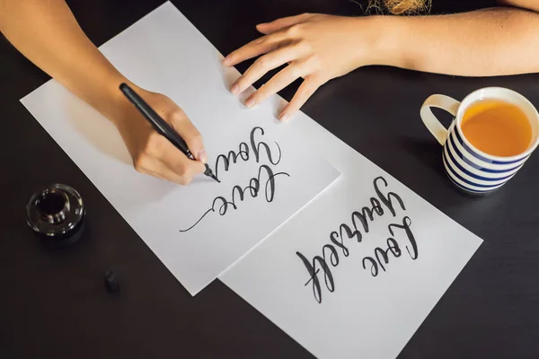 Hou van jezelf. Kalligrafie jonge vrouw schrijft zin op wit papier. Het schrijven van sier versierde letters. Kalligrafie, grafisch ontwerp, belettering, handschrift, creatie concept — Stockfoto