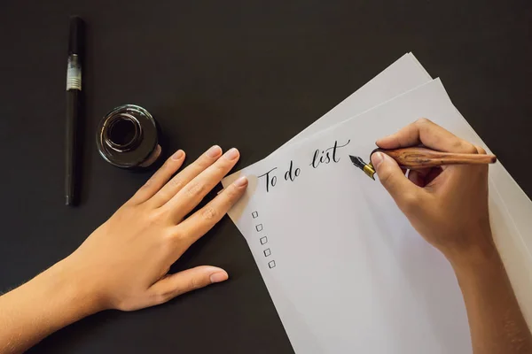 Para fazer a lista. A calígrafa Young Woman escreve uma frase no white paper. Inscrição de letras ornamentais decoradas. Caligrafia, design gráfico, letras, caligrafia, conceito de criação — Fotografia de Stock